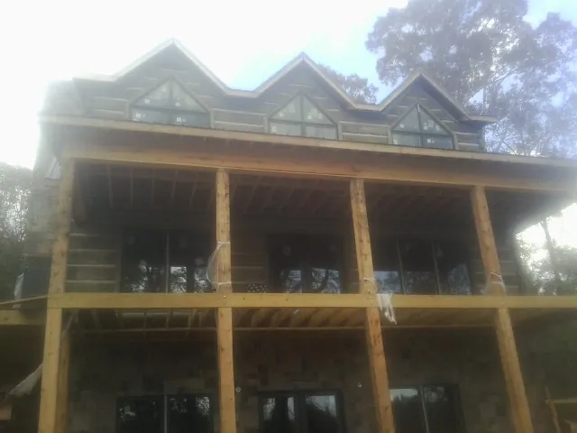 Dormers and porch framing on a large log home under construction — Roof Coating work by our crew in Hooper