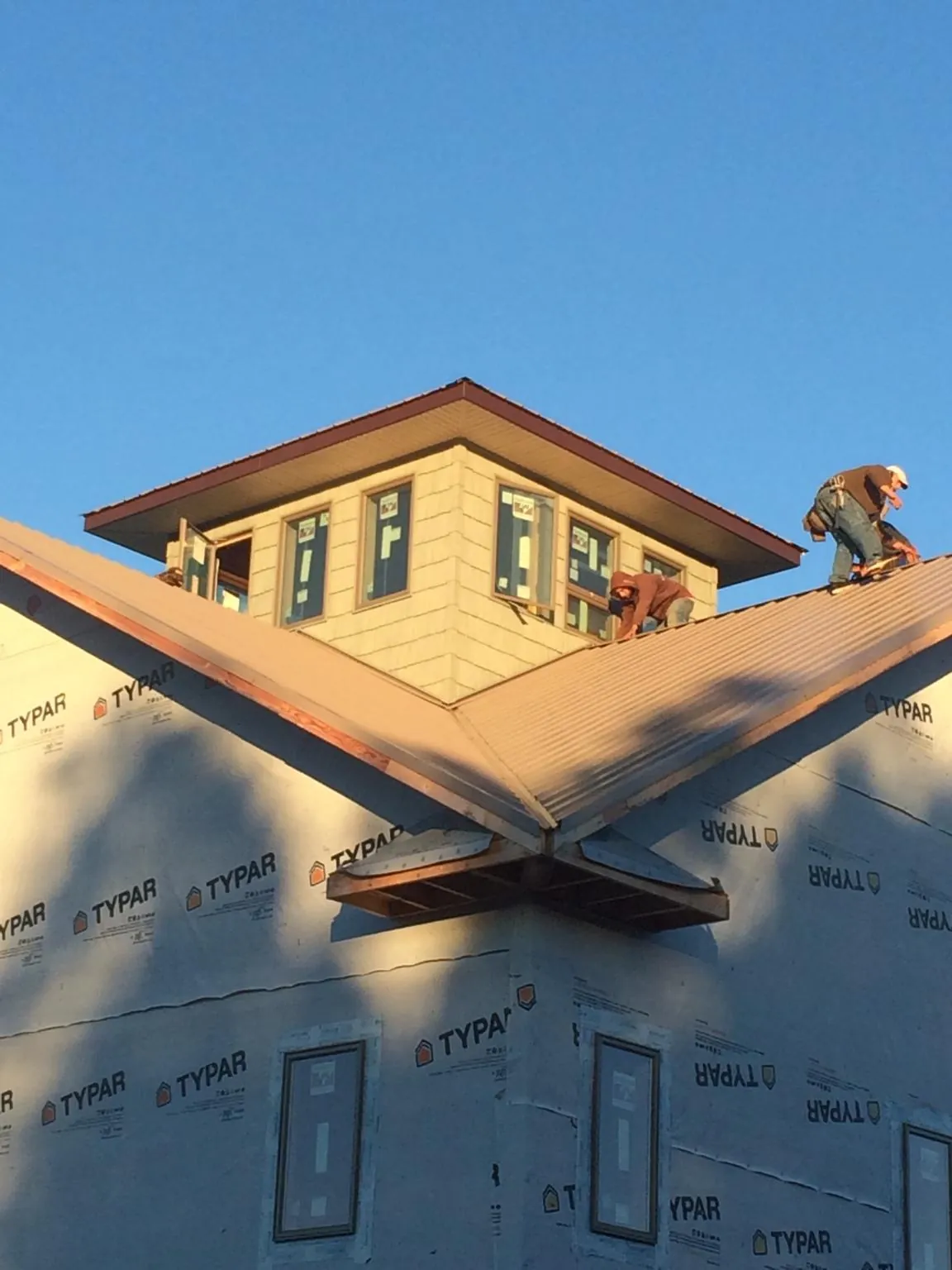 Roofers working around a rooftop cupola on a new metal roof at sunset — Roof Waterproofing in Hooper by Roofing Brothers